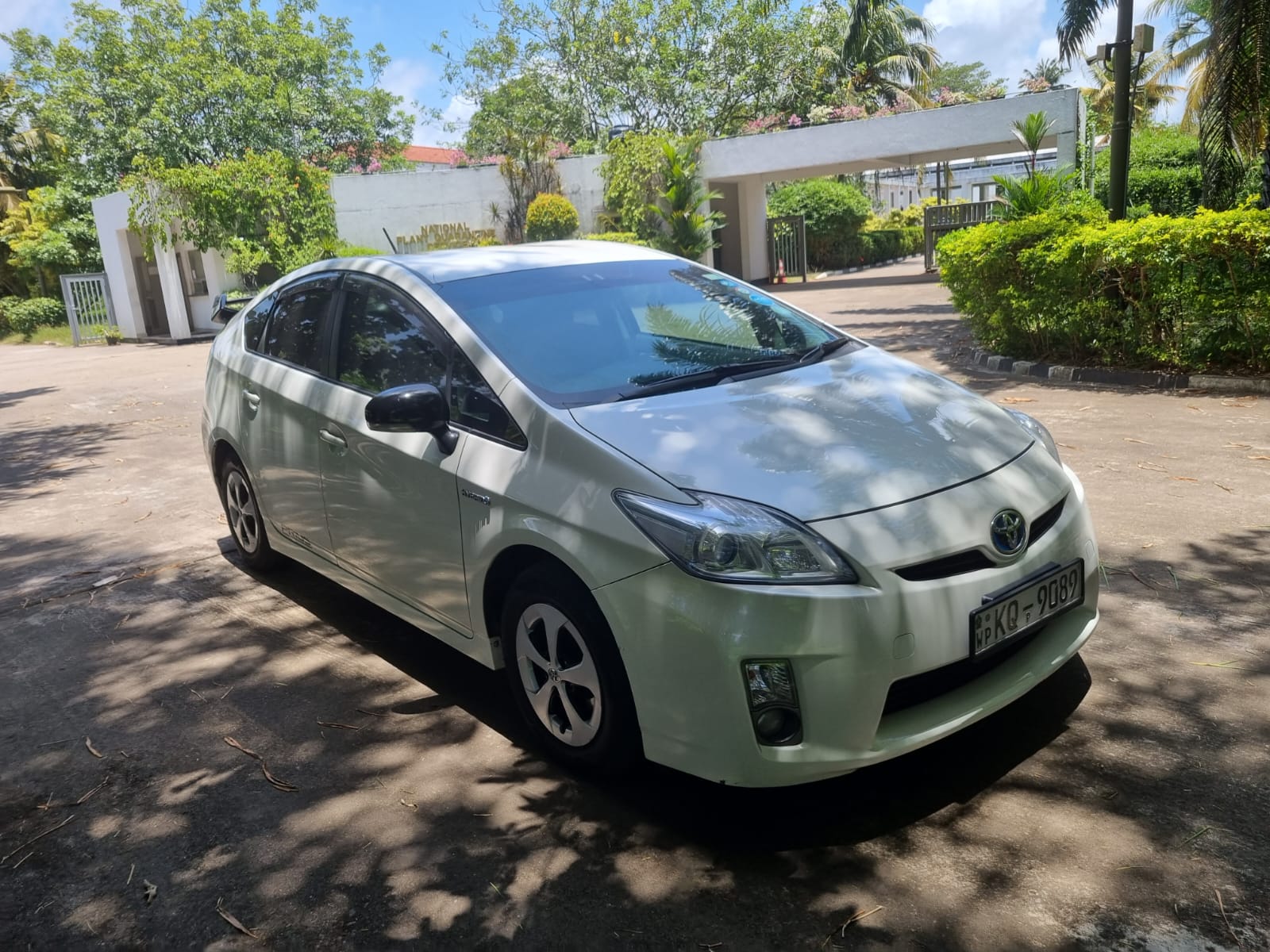 A white Toyota Prius parked in front of a residential house, showcasing its sleek design and eco-friendly features.