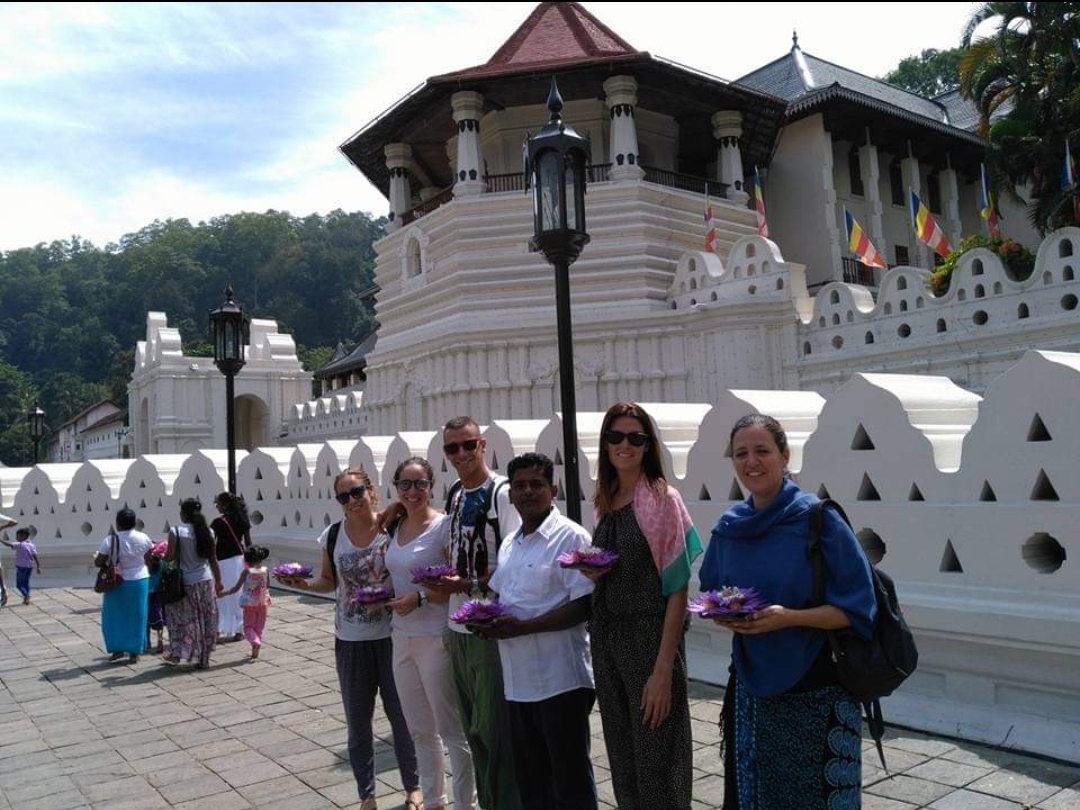 A diverse group of individuals gathered in front of a majestic temple, showcasing cultural unity and architectural beauty.