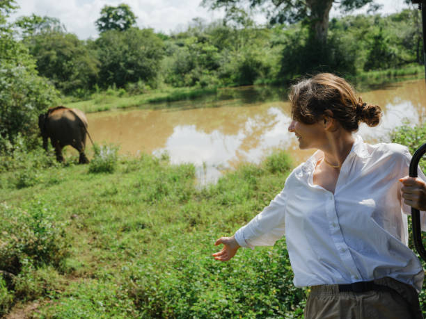 A woman stands gracefully in front of a large, leafy tree, showcasing a serene connection with nature.